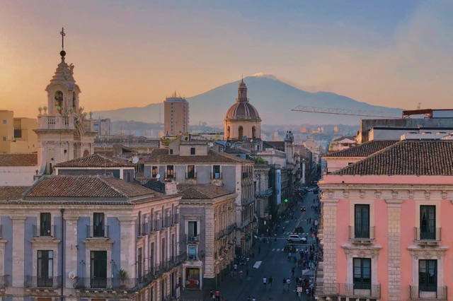 Panorama di Catania al tramonto con i tetti barocchi e l'Etna sullo sfondo