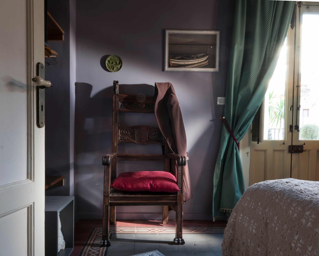 Antique carved armchair with burgundy cushion in Room Pirandello 